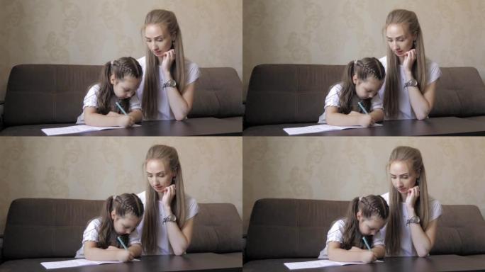 妈妈和她的学龄前女儿一起在家做作业，妈妈帮助5岁的女孩做学龄前任务，在笔记本上写信。儿童教育理念。支