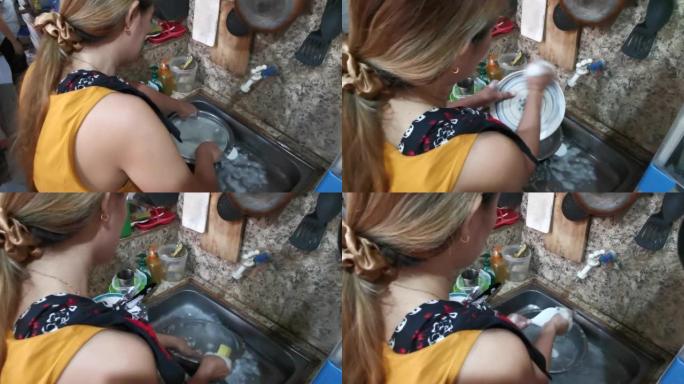 亚洲妇女在不整洁的厨房盥洗盆里洗碗。