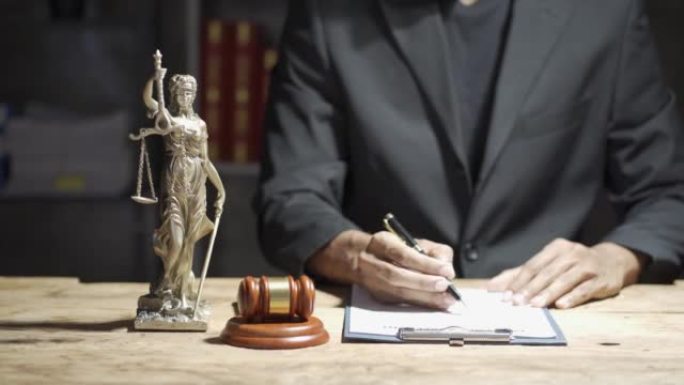 律师在办公室处理带有黄铜秤和锤子的合同文件。法律、法律服务、咨询、司法和法律概念。具有服务概念的律师