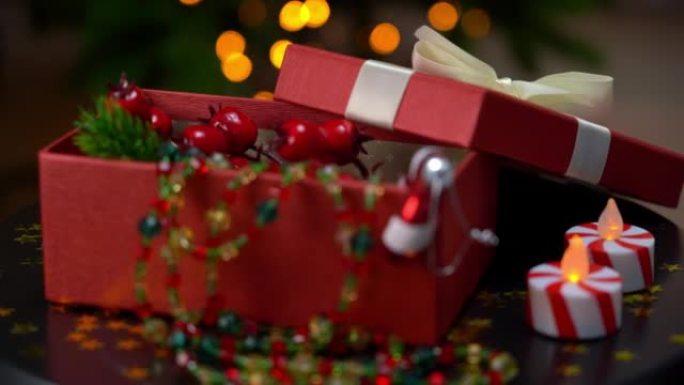 带有圣诞装饰品礼物的红色打开盒的特写在托盘上旋转