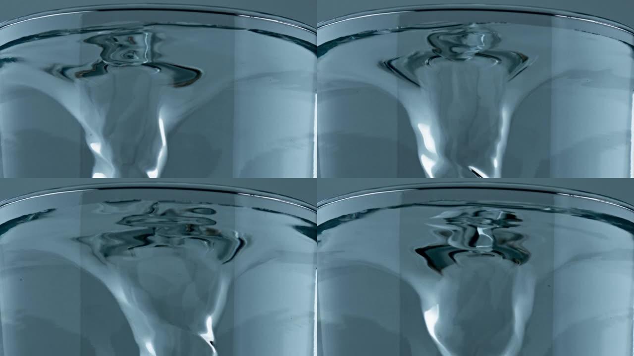 矿物饮料纺丝透明圆筒特写。纯水涡流玻璃