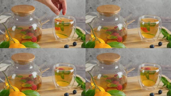 女人做水果泡茶，把覆盆子和薄荷叶放进杯子里，放清爽的绿茶，横向4k视频剪辑