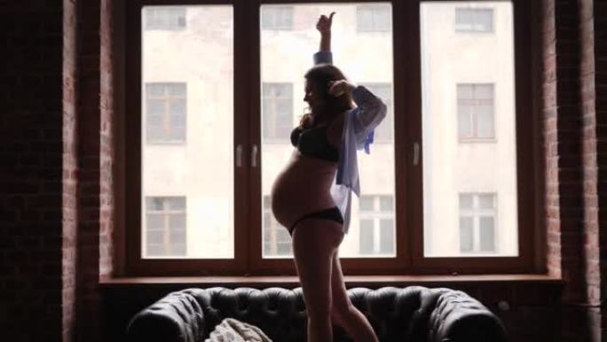 怀孕之美 -- 年轻女性剪影留在明亮的窗户旁