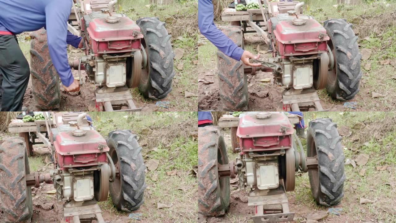 一名男性农民正在转动启动农业发动机的杠杆。皮卡后面的发动机。
