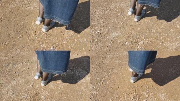 穿着运动鞋和黑色紧身衣的女人的脚在公园的碎石路上