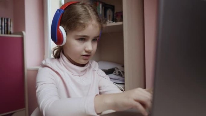 远程学习。使用笔记本电脑在线学习的女学生。学生戴着耳机看互联网课程。未来的程序员学习编程。玩电脑游戏