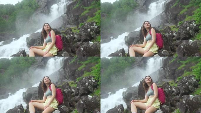 坐在挪威山区强大瀑布附近的女人的特写肖像