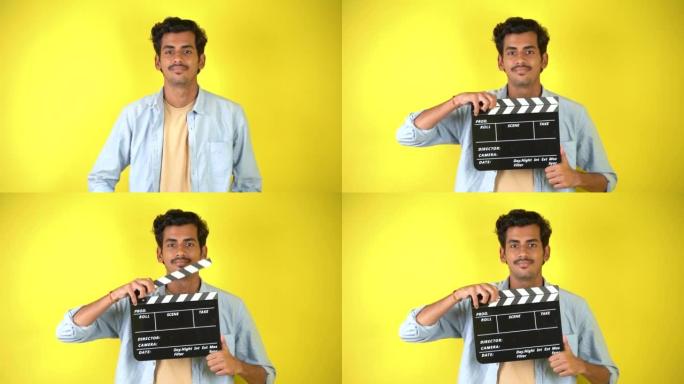 开朗的年轻亚洲印度男子站在隔板上，拍板用于电影制作，孤立在彩色背景工作室肖像上