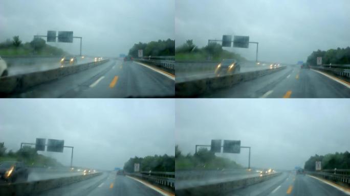 在雨中，在阴沉的天气里，在高速公路上行驶。雨刮器擦拭汽车雨水浸湿的挡风玻璃。