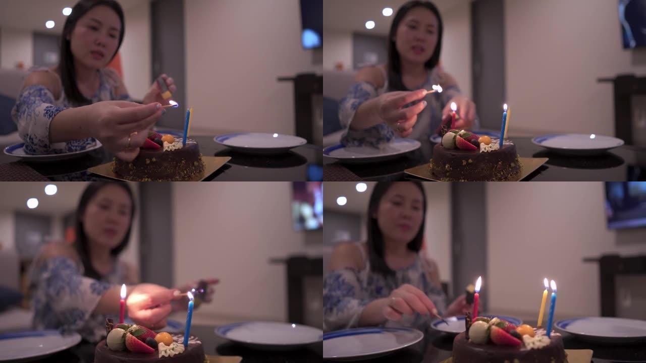 泰国女性在装饰有浆果的巧克力蛋糕上点燃五颜六色的蜡烛
