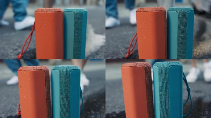 两个便携式音乐扬声器橙色和蓝色并排支架配对一起播放音乐响亮的低音街道城市声音