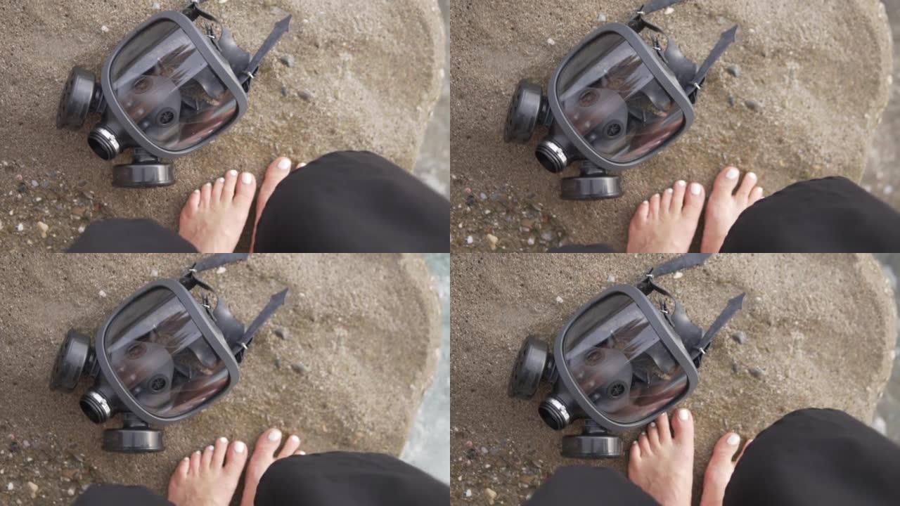 防毒面具躺在一块石头上，背景是海边海滩上妇女的脚