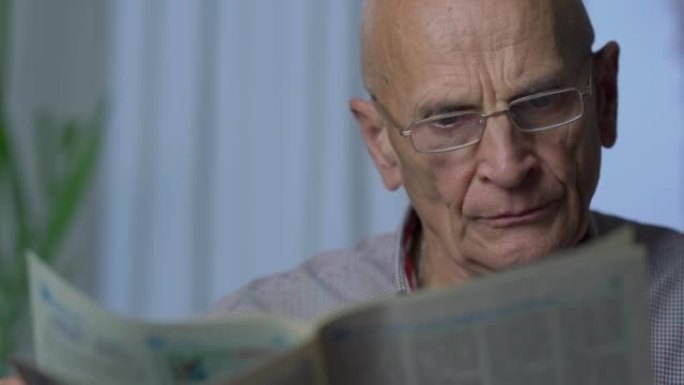 老爷爷戴着眼镜一边看报纸一边享受