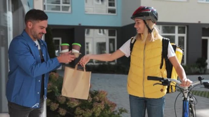 快乐女人骑着自行车，用纸袋将咖啡和食物运送到顾客家中。送餐概念。