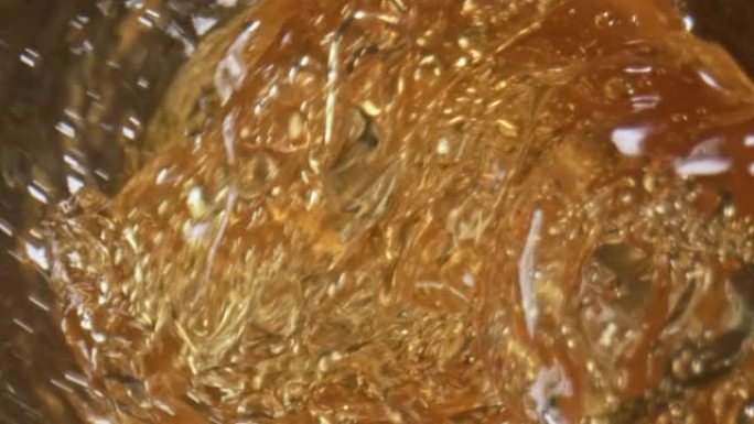 玻璃器皿特写镜头内的金色麦芽酒。大麦液体飞溅浇注玻璃
