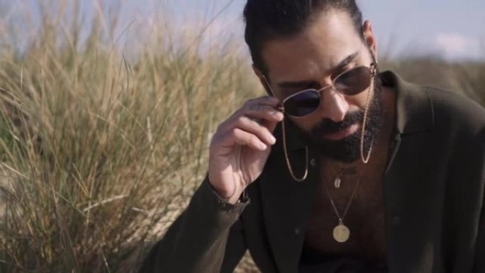 阳光明媚的日子，一个迷人的中东男人在海滩上留着胡须的特写镜头