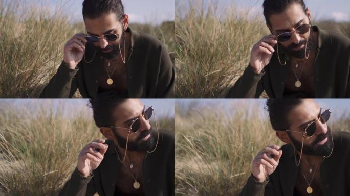 阳光明媚的日子，一个迷人的中东男人在海滩上留着胡须的特写镜头
