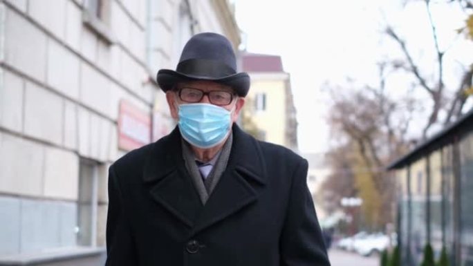 一位老人戴着防护口罩走在街上。社交距离上的人类生活。