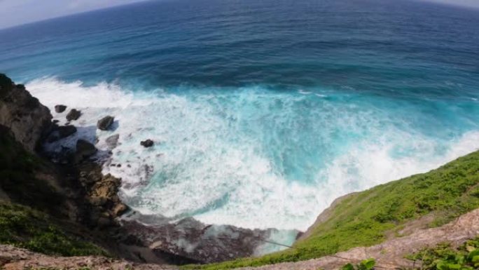 俯瞰岩石悬崖和海洋。岛上的天堂离子。波浪在岩石上滚动，以巨大的力量击中它。产生了大量的泡沫水。