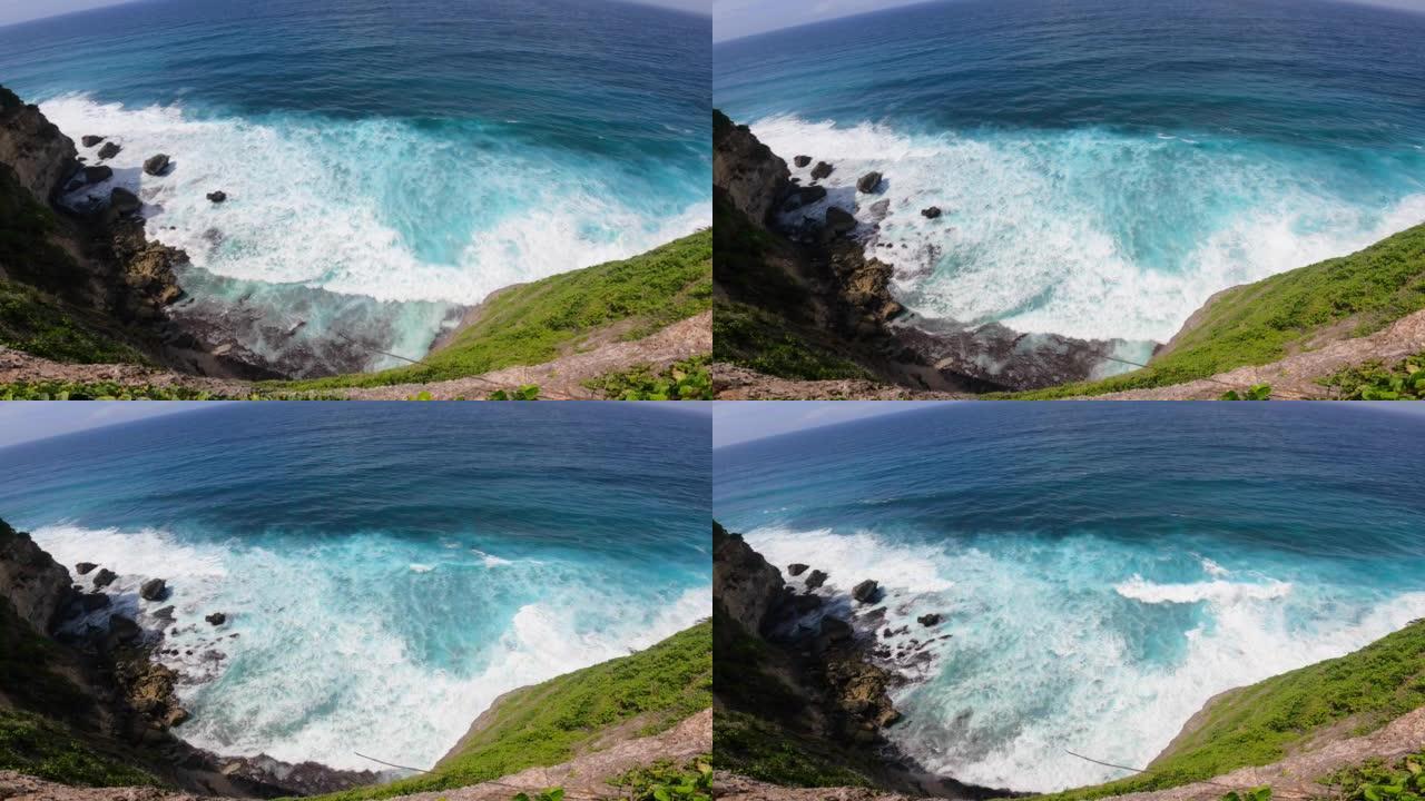 俯瞰岩石悬崖和海洋。岛上的天堂离子。波浪在岩石上滚动，以巨大的力量击中它。产生了大量的泡沫水。