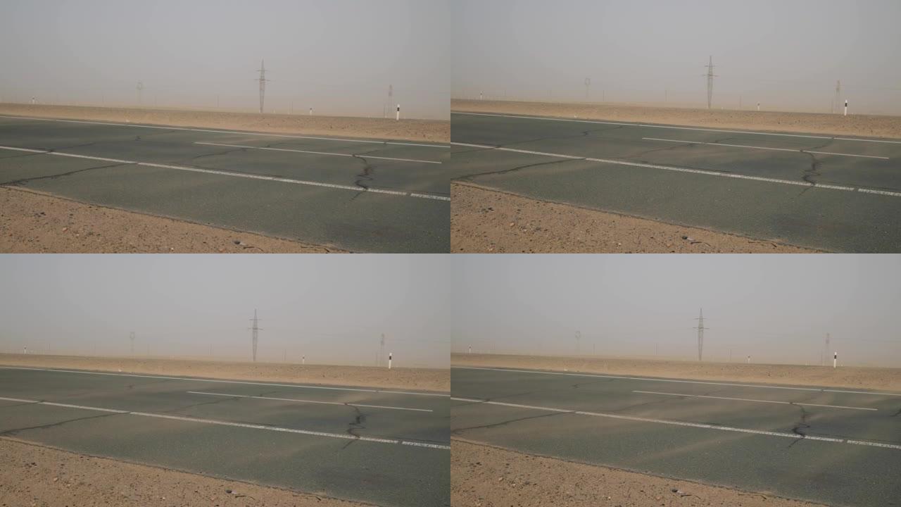道路上的沙子漂浮，而沙漠地区的狂风