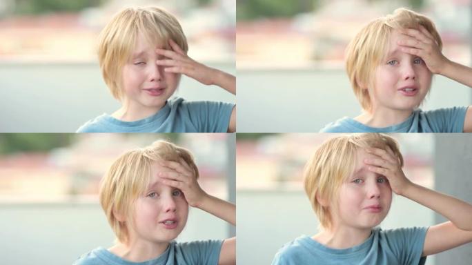 哭泣的学龄儿童的特写肖像。金发可爱的男孩生气并发誓。真实的情感。心烦意乱，得罪和悲伤的孩子