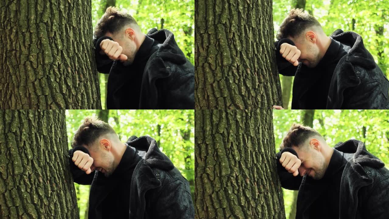 特写沮丧的男性脸悲伤的压力男人站在树林里的户外抱着头，因为深深的沮丧而哭泣，冒犯了面部表情担心麻烦问