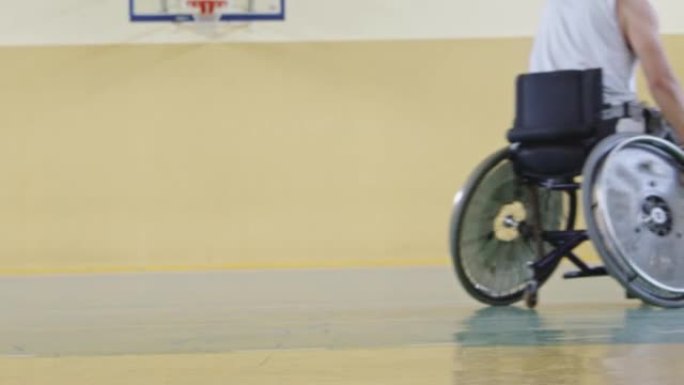 一个运动的残疾人坐在轮椅上在学校体育馆打篮球队的特写镜头。有选择性的重点。