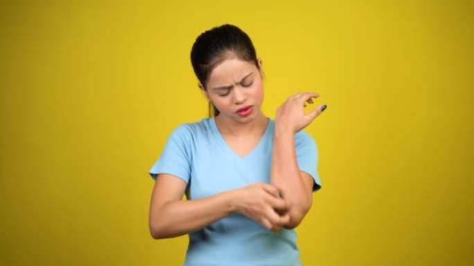 年轻女性有皮肤问题，皮肤刺激，皮肤感染瘙痒红疹，手臂用手抓挠，孤立超过黄色背景