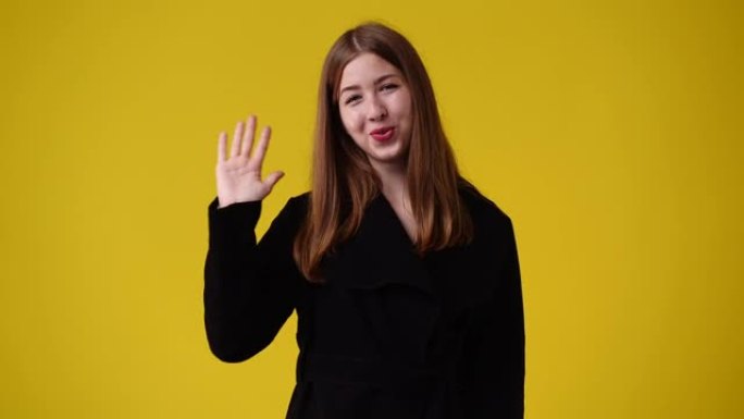 黄色背景上可爱的女孩挥手打招呼的4k视频。