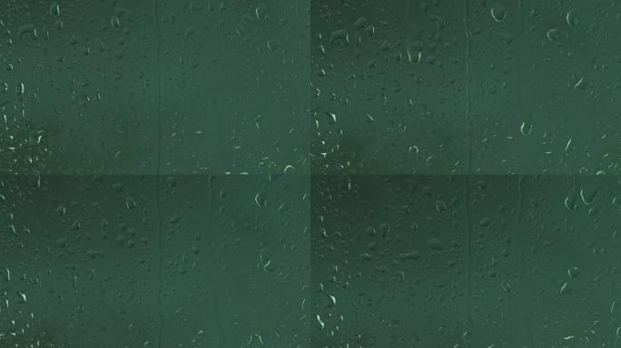水滴顺着墨绿色背景的玻璃流下，特写