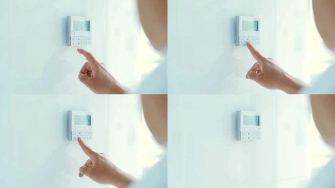 特写男人的手控制并按下按钮公寓和办公室的空调和供暖控制面板位于白色的墙壁上。