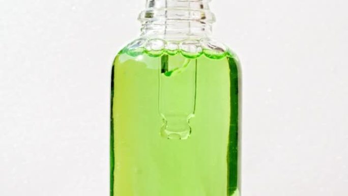 透明的化妆品凝胶液，在移液器中带有气泡，滴入瓶中。天然有机化妆品，医药。生产特写。慢动作