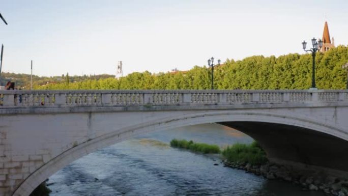 在阳光明媚的夏日傍晚，维罗纳加里波第桥下的阿迪杰河流水