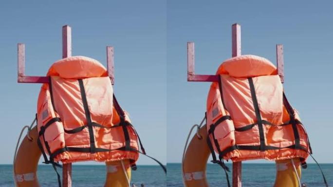 救生圈和救生衣挂在海景海滩上的柱子上。