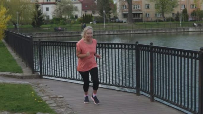 高级退休女性在湖道户外慢跑阳光明媚的白天城市公园