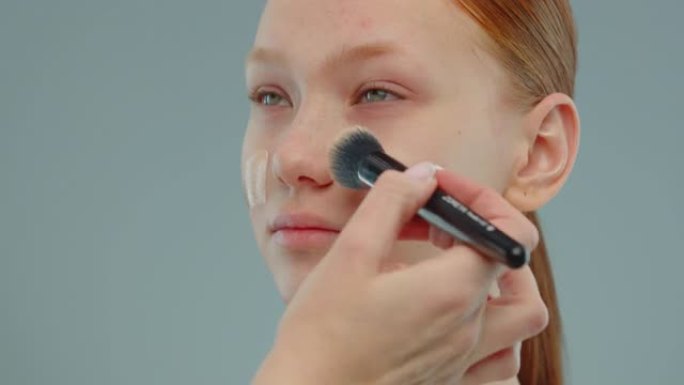 化妆师手用抹刀将色调粉底涂在模特的脸上。