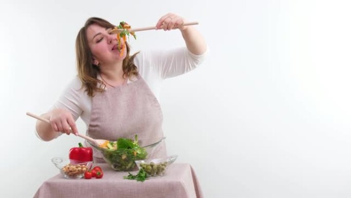 有趣开朗的女人吃沙拉木勺东西部分食物减肥广告健康食品素食女人全身多汁横幅白色背景玻璃器皿食欲好