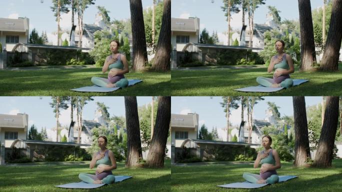 做瑜伽的孕妇坐在莲花的位置用手在怀孕的肚子上练习呼吸练习