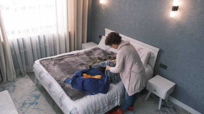 成熟的女人正在床上打包旅行包和背包