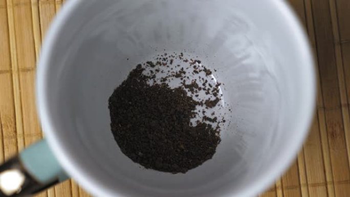 速溶黑咖啡颗粒落在白色杯子的底部。早上煮咖啡。煮咖啡的过程。