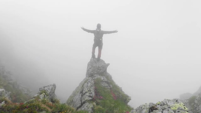 勇敢的单人徒步旅行者站在法加拉斯山脉的悬崖边缘，周围有浓雾