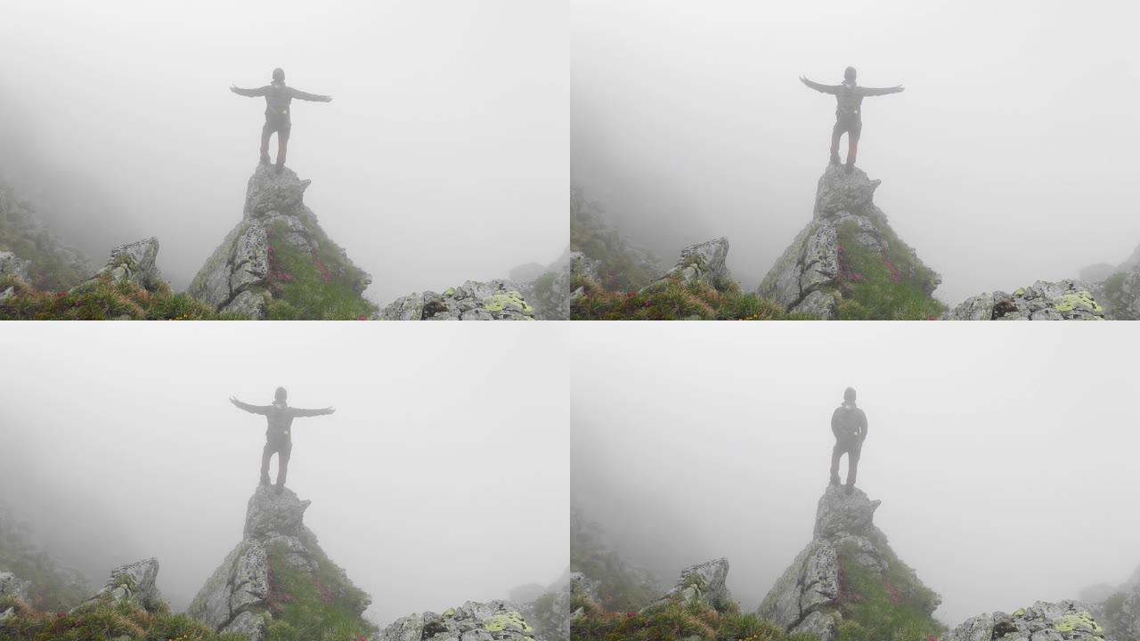勇敢的单人徒步旅行者站在法加拉斯山脉的悬崖边缘，周围有浓雾