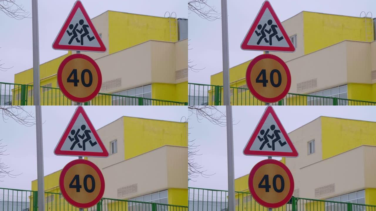 “告诫儿童” 和 “限速40” 的路标站在一所学校旁边