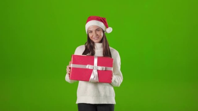 穿着圣诞老人帽子的女人在工作室与圣诞礼物合影