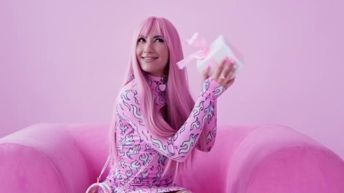 粉红色头发的魅力女人在室内拿着礼品盒。快乐时尚女性