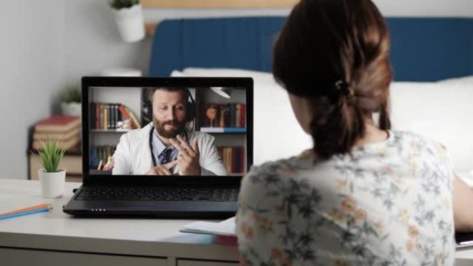 医生在线连接。女人坐在笔记本电脑前的桌子旁，通过互联网视频连接与穿着白大褂的男医生交谈，女孩在笔记本