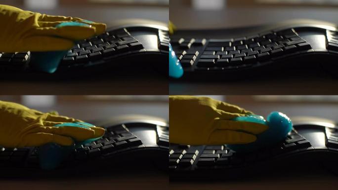 戴着黄色手套的无法识别的年轻人的特写镜头使用蓝色粘液吸收凝胶，慢动作清洁和清除黑色pc键盘上的灰尘。