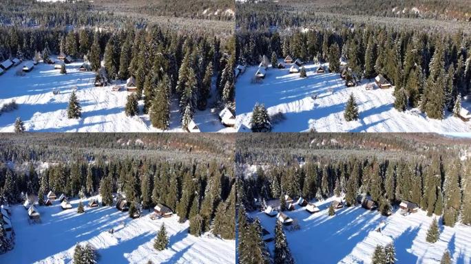 山里白雪皑皑小屋的鸟瞰图。白雪皑皑的冬季景色，光线从树上漏出。美丽的山间小屋或小屋在冬季森林中被雪覆