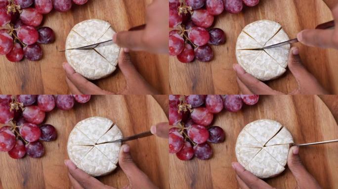 在木制背景上切割新鲜的山羊奶酪和葡萄果实。